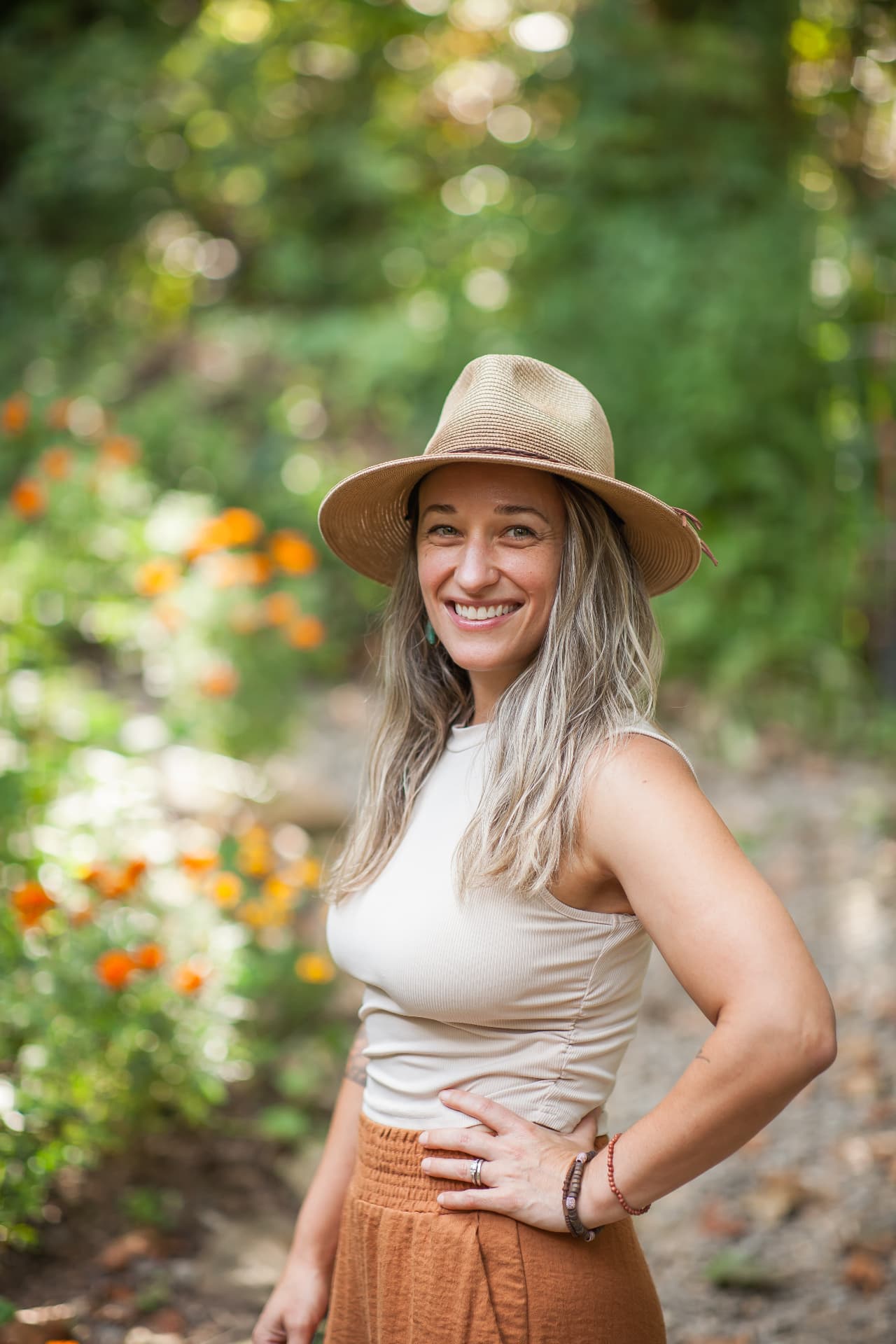 Jules Sawyer smiling in a summer garden full of orange wildflowers near Asheville